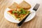 Slices of bread, piece of omelette with tomatoes, green onion and dill, fork in plate on wooden table