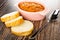 Slices of bread, pink bowl with squash caviar, spoon on wooden table