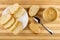 Slices of bread in plate, sandwich with peanut paste, spoon, jar with peanut butter on bamboo table. Top view