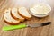 Slices of bread with raisin  white bowl with creamy cheese  knife on wooden table