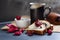 Slices of butter poppy roll, served with cherry jam and large ceramic cup with hot drink.