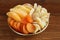 Slices of candied ginger root, pieces of dried mango fruits and dried apricots lying on a golden plate on a wooden table.