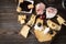 Slices of cheese, cracker, ham, jam, grapes, olives, on a dark wooden background, appetizer for wine