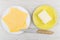 Slices of cheese in plate, butter in saucer, kitchen knife