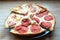 Slices of different pizza with bacon, pepperoni sausages, mushrooms and cheese on a plate and a wooden background