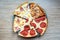 Slices of different pizza with bacon, pepperoni sausages, mushrooms and cheese on a plate and a wooden background. Top view