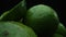 Slices of fresh lime are arranged in a pile with a black background. Comestible.