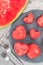 Slices of fresh seedless watermelon cut into heart shape on slate board, flat lay, vertical