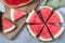 Slices of fresh seedless watermelon cut into triangle shape laying on wooden plate, flat lay, horizontal