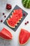 Slices of fresh watermelon on the black plate, cherries and pieces of watermelon on the concrete background.