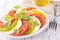 slices of green and red tomato with slice of mozzarella and basil- Caprese salad