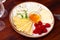 Slices of hard and soft cheeses on plate with raspberries and honey