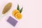 Slices of juicy orange, a body brush and handmade lavender soap on a pink background. The concept of home Spa