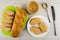 Slices, loaf of bread on cutting board, jar with peanut butter, sandwiches with peanut paste in plate, spoon, knife on wooden