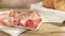 slices of mortadella on a white plate. italian sausage on a wooden table with bread. serving meat delicacy