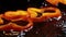 Slices of orandge bell pepper fall down on brown wooden board with water drops