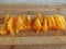 Slices of orange tomato on the wooden background in macro. Chopped tomato on a cutting board.