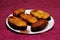 Slices of Rohu fish fry over maroon paper