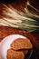 Slices of rye wholegrain bread on white plate, wheat ears on wooden boards background, rustic kitchen table. Homemade bread,