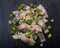 Slices of Salted Boneless wild-caught Atlantic Herring garnished with Chopped Green Onion Scallions. Black natural stone