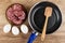 Slices of sausage in plate, spatula in frying pan, eggs on table. Top view