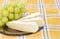 Slices of a soft cheese and white table grapes closeup