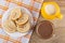 Slices of swiss roll in plate on napkin, jug of milk, cocoa with milk in cup on table. Top view