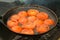 Slices of tomates is frying on frying pan with oil in grill, top view.