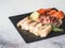 Slices of various salted fish - salmon, muksun, oily fish on a black slate board on a gray background. Copy space