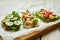 Slices of waffle bread with different vegetables, shrimp and seasoning