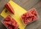 Slices of watermelon on yellow cutting board and wooden table.