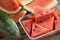 Slices of watermelon on yellow cutting board and wooden table.