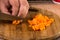 Slicing cooked carrot with knife in hand on the wooden board