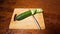 Slicing cucumber. Closeup of chopped vegetables on wooden cutting board. Stop motion animation