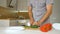 Slicing green bell pepper on wooden cutting board. Male hand cuts capsicum with knife. Man is cutting the sweet