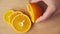 Slicing an orange fruit on a kitchen cutting Board, wooden table as background, close view.