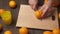 Slicing an orange on a kitchen cutting Board, wooden table as background, close view. Glass of orange juice.