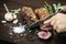 Slicing organic roast beef roll on wood table with ingredients