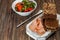 Slicing smoked meats on a board with rye bread. Making a sandwich. On a wooden background.