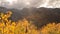 Slide rail shot of yellow aspens and rugged mountain peaks
