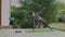 Slide right shot of healthy Caucasian woman practicing yoga pose by laptop in backyard