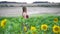Slide right shot of young woman strolling in beautiful sunflower field