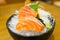 Slide salmon sashimi on ice in black bowl.