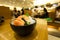 Slide salmon sashimi on ice in black bowl.
