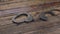 Slider shot. Iron handcuffs with a key lying on a wooden table.