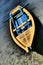 Slightly faded yellow fishing boat with blue interior, oars and vertical wooden oar support