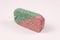 a slightly oblique side view of a green-pink pumice stone that stands on its side