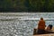 Slightly overweight young woman with a discarded black hat on the banks of the Main River, whose waves shimmer in the sun