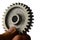 Slightly used alluminium alloy cog wheel from spur gear held in left hand on white background