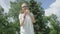 Slim attractive bespectacled girl with blonde hair and blue eyes practices in blowing soap bubbles standing in front of